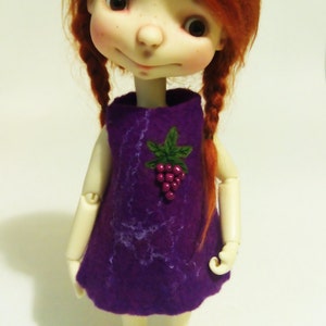 May include: A doll with red hair wearing a purple dress with a grape design. The doll is wearing purple shoes.