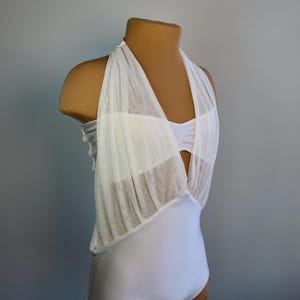 May include: White halter top with a sheer overlay and a fitted bodice. The top has a keyhole opening in the back and a ruffled hem.