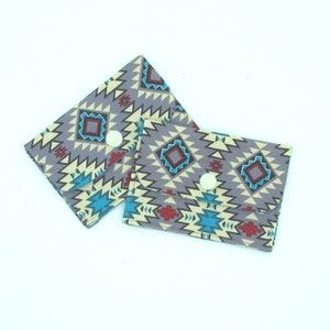 May include: Two small fabric wallets with a geometric pattern in shades of gray, blue, red, and yellow. The wallets have a button closure.