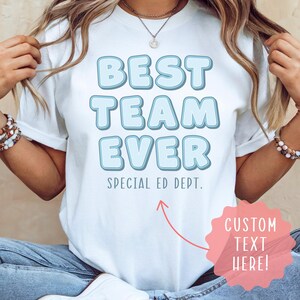 May include: White t-shirt with the text "BEST TEAM EVER" in light blue bubble letters. Below the text is "SPECIAL ED DEPT." A pink starburst graphic with the text "CUSTOM TEXT HERE!" is in the lower right corner.