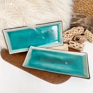 Op de afbeelding: Set van drie keramische mokken met een gespikkelde, matte afwerking. De mokken zijn in blauwe, groene en witte tinten. Elke mok heeft een eenvoudig, modern ontwerp, perfect voor koffie of thee.