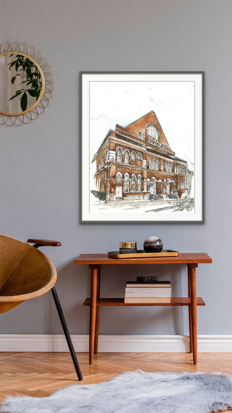Puede incluir: Una ilustraci&oacute;n de acuarela de un edificio de ladrillo con ventanas arqueadas y una gran ventana redonda. El edificio est&aacute; enmarcado en un marco gris y cuelga de una pared gris.