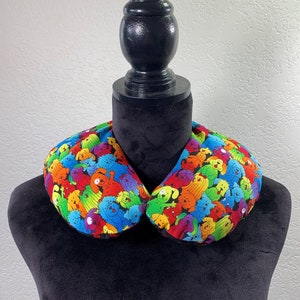 May include: A black fabric collar with a colorful print of cartoon dogs. The collar is on a black mannequin.