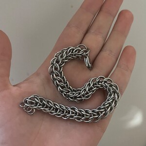 May include: A silver chainmail bracelet with a clasp closure.