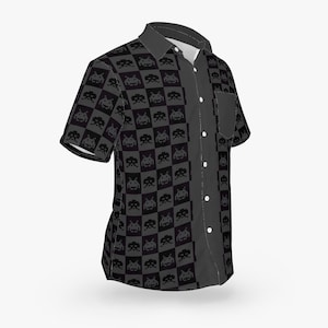 May include: A short-sleeved button-up shirt with a black and gray checkerboard pattern featuring pixelated alien figures. The shirt has a dark gray pocket and a contrasting dark gray panel down the front with white buttons. The collar is dark gray.