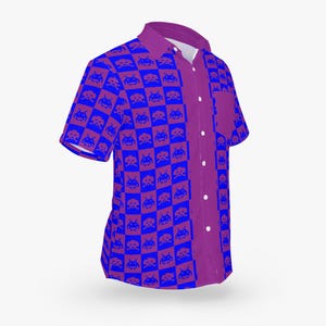 May include: A short-sleeved button-down shirt with a vibrant pattern. The shirt features a checkerboard design of blue pixelated alien figures on a red background. The collar, pocket, and button strip are solid purple.