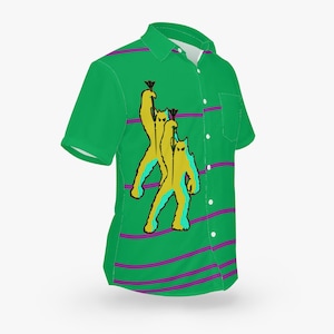 May include: Green short-sleeved button-down shirt with purple stripes and a graphic print of three yellow cartoon monsters holding spears.
