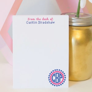 May include: A white notepad with the text "From the desk of: Caitlynn Bradshaw" at the top. The notepad has a blue and pink monogram with the letters "CBP" in a circle with a dotted border.