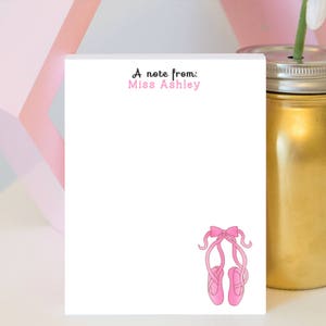 May include: A white notepad with the text "A note from: Miss Ashley" at the top. The notepad has a pink ballerina shoe illustration at the bottom.