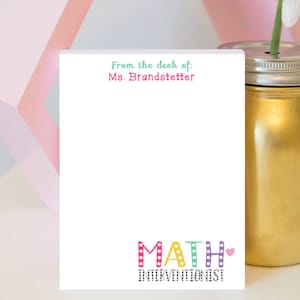 May include: White notepad with the text "From the desk of: Ms. Brandstetter" at the top. The bottom of the notepad has the word "MATH" in colorful letters with polka dots and the text "Interventionist" below.