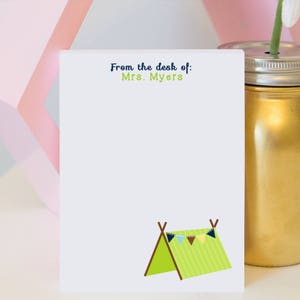 May include: White notepad with the text "From the desk of: Mrs. Myers" at the top. The notepad has a green and white tent with brown poles and a string of colorful flags at the top.