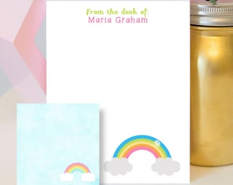 Può includere: Un set di cartoleria personalizzata con un design arcobaleno. La cartoleria include un foglio di carta con il testo "From the desk of: Maria Graham" e un foglio di carta più piccolo con un arcobaleno e nuvole.
