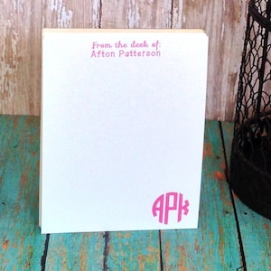 Könnte beinhalten: Weißer Notizblock mit rosa Text, der "From the desk of: Afton Patterson" lautet, und einem rosa Monogramm "APK".