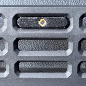 May include: Black plastic modular panel with a small black rectangular accessory with a gold screw in the center.