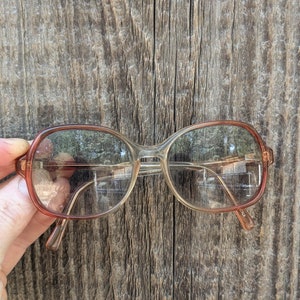 May include: A pair of brown and clear plastic eyeglasses with a rounded square frame.