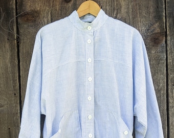 May include: A white and blue striped button-up shirt with a stand-up collar and long sleeves. The shirt has a relaxed fit and a slightly cropped length.