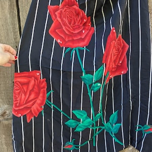May include: Black and white striped fabric with a red rose pattern. The roses have green leaves and stems.