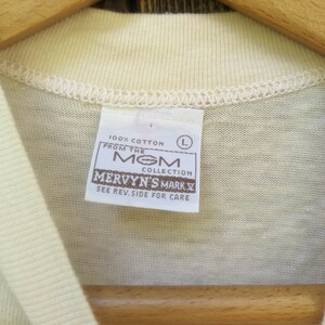 May include: A white 100% cotton t-shirt tag with the text "From the MOM Collection Mervyn's Mark V See Rev. Side for Care" and a size L label.