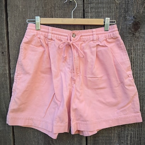 Puede incluir: Un pantalón corto de algodón rosa con cintura de cordón y cierre de botón. El pantalón corto tiene un corte holgado y es perfecto para el clima cálido.