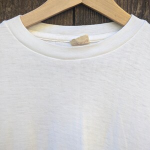 May include: White t-shirt with a small white tag sewn into the neckline.