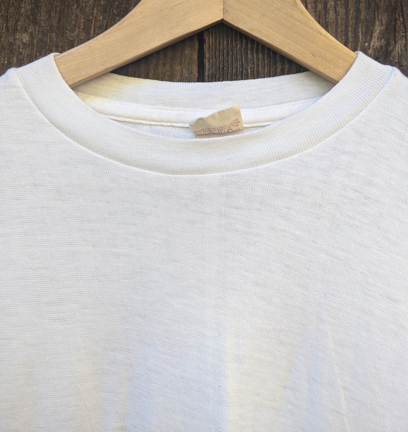 May include: White t-shirt with a small white tag sewn into the neckline.