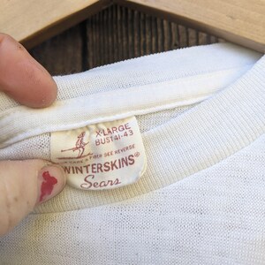May include: White t-shirt with a red tag that says "X-Large Bust 41-43" and "Winterskins Sears" with a skier graphic.