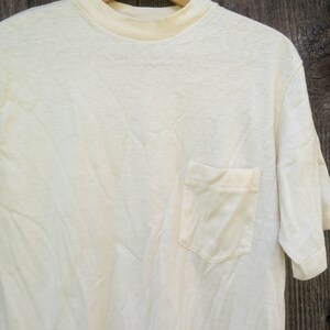 May include: A plain white t-shirt with a single pocket on the left side. The shirt is made of a soft, comfortable fabric and has a crew neck.