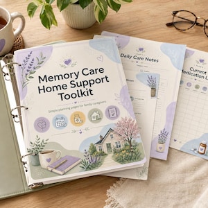 May include: A light green binder with a "Memory Care Home Support Toolkit" cover, featuring a house illustration and lavender accents. Includes daily care notes and medication list pages, along with a cup of tea and eyeglasses.