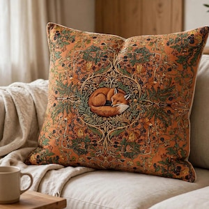 May include: A square throw pillow featuring a vibrant orange background with a detailed pattern of green leaves, brown acorns, and berries. In the center, a circular frame encloses a sleeping fox curled up in a ball, rendered in warm tones.