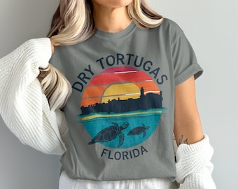 May include: Gray t-shirt with a vintage-style graphic of a sunset over Dry Tortugas, Florida. The graphic includes the text "Dry Tortugas Florida" and two sea turtles.