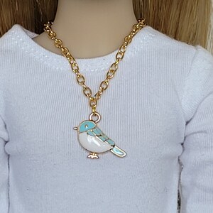May include: A gold chain necklace with a blue and white enamel bird pendant.