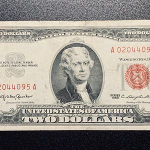 May include: A vintage two-dollar bill featuring a portrait of Thomas Jefferson. The bill has the text "TWO DOLLARS" and "UNITED STATES OF AMERICA". The bill is from the 1963 series and has the serial number A 02044095 A.