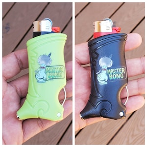 Może przedstawiać: Dwa zapalniczki Master Bong, jeden zielony, a drugi czarny, z kreskówkowym wzorem bonga i tekstem "Master Bong".