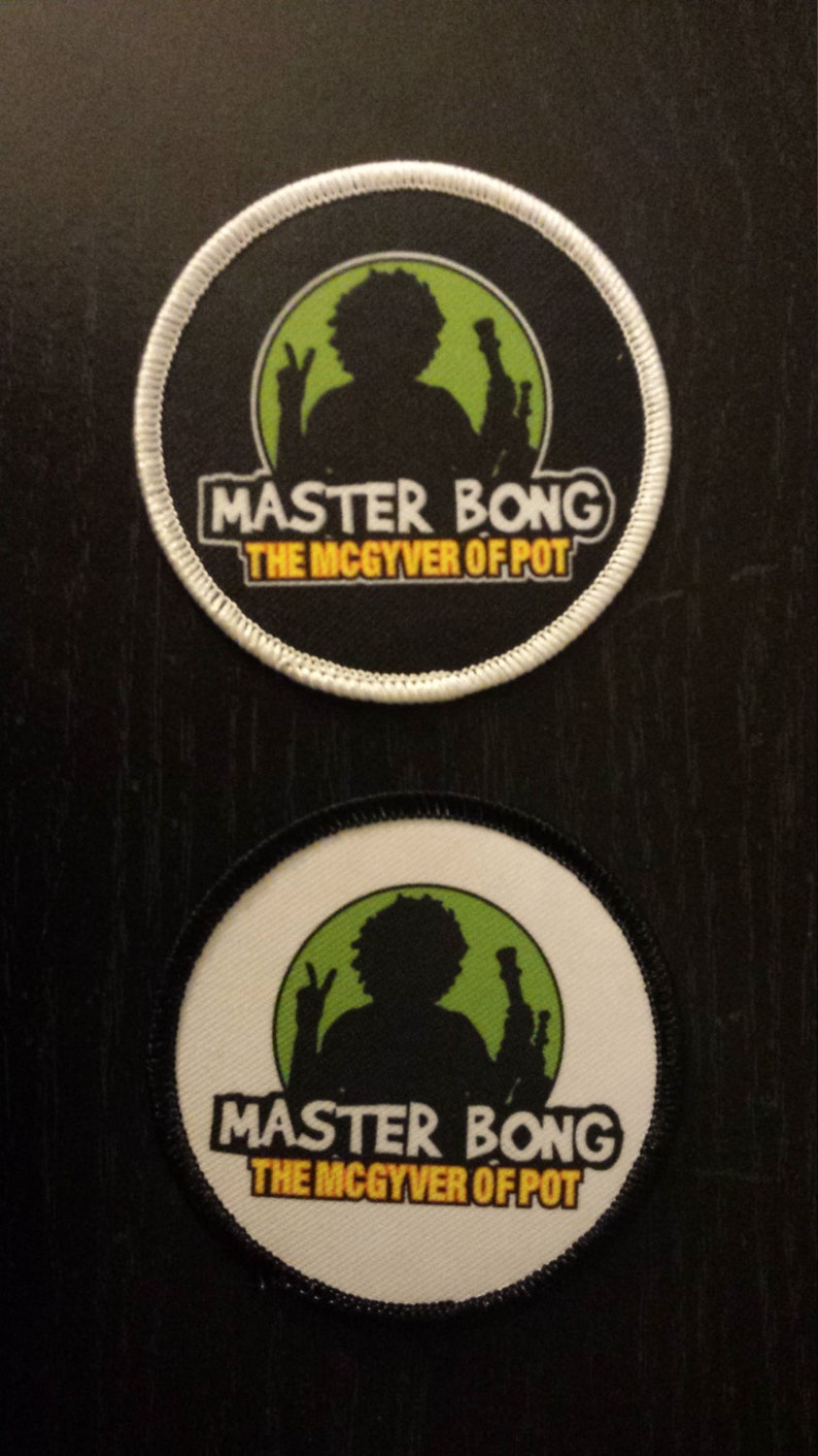 Peut inclure: Deux patchs ronds noirs et blancs avec un cercle vert au centre. Le cercle repr&eacute;sente une silhouette d'une personne tenant un bang. Le texte "Master Bong The McGyver of Pot" est imprim&eacute; en jaune sur les patchs.