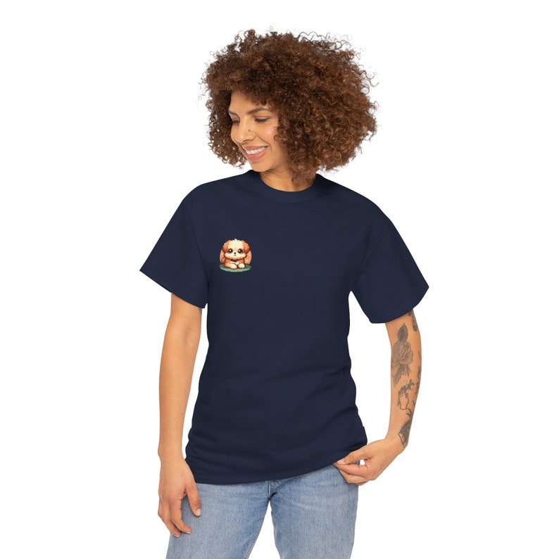 May include: Navy blue t-shirt featuring a small embroidered illustration of a cute, cartoon-style Shih Tzu puppy. The puppy is light brown and tan, sitting on a patch of green. The t-shirt is a simple, classic crew neck style, suitable for casual wear.