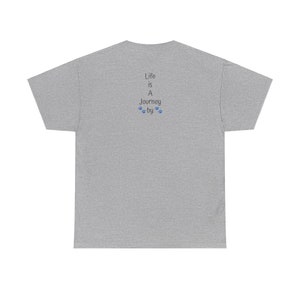 May include: Back view of a heather gray unisex t-shirt featuring a vertical text design. The text reads: 'Life is A Journey by' with small paw prints in blue between 'Journey' and 'by'. The shirt is a relaxed fit, short-sleeved tee.