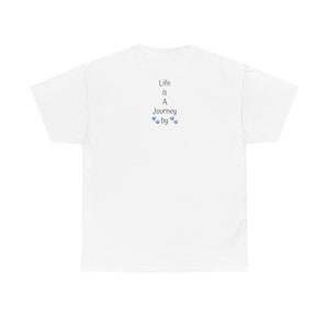May include: White unisex t-shirt featuring a minimalist design on the back. The text 'Life is A Journey by' is printed in gray, accompanied by small blue paw prints. The shirt is a simple, casual style, suitable for everyday wear.  The design is subtle and understated, making it a versatile option for various occasions.