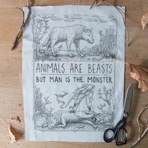 Könnte beinhalten: Ein rechteckiges hellgraues Stoffpaneel mit einer schwarzen Tuschezeichnung. Oben ist ein Wolf in einer Landschaft zu sehen. Der Text lautet ANIMALS ARE BEASTS BUT MAN IS THE MONSTER. Unten steht eine Figur mit Gewehr über einem toten Wolf.