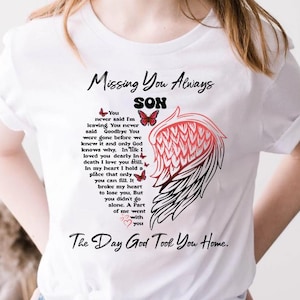 May include: White t-shirt with the text "Missing You Always SON" and a poem about loss. The design includes a red and black wing graphic and butterfly illustrations. The shirt is a crew neck.