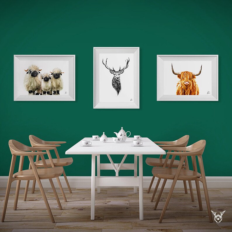 May include: Three framed animal illustrations on a green wall above a white dining table with four chairs. The illustrations are of a Highland cow, a stag, and two sheep.