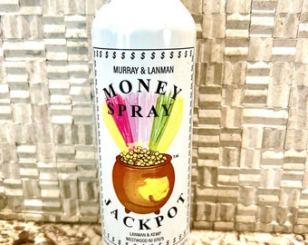 May include: White aerosol can with a gold and red label. The label says "Money Spray Jackpot" and features a pot of gold coins with a rainbow above it. The can is 8 ounces.