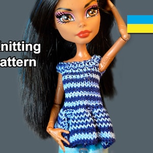 May include: Knitting pattern for a blue and white striped doll top with a pocket. The doll is wearing the top and has long black hair. The image also includes the Ukrainian flag.