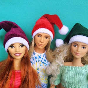 Puede incluir: Tres mu&ntilde;ecas con gorros de Pap&aacute; Noel. Las mu&ntilde;ecas llevan un gorro de Pap&aacute; Noel rojo, burdeos y verde. Las mu&ntilde;ecas tienen el pelo largo y miran a la c&aacute;mara.
