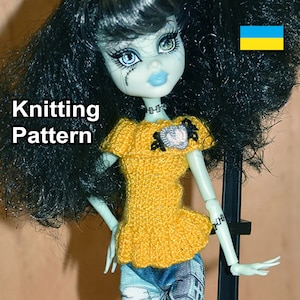 May include: Knitting pattern for a yellow doll top with a heart-shaped embellishment. The doll has black hair and green skin. The text "Knitting Pattern" is visible in the image.