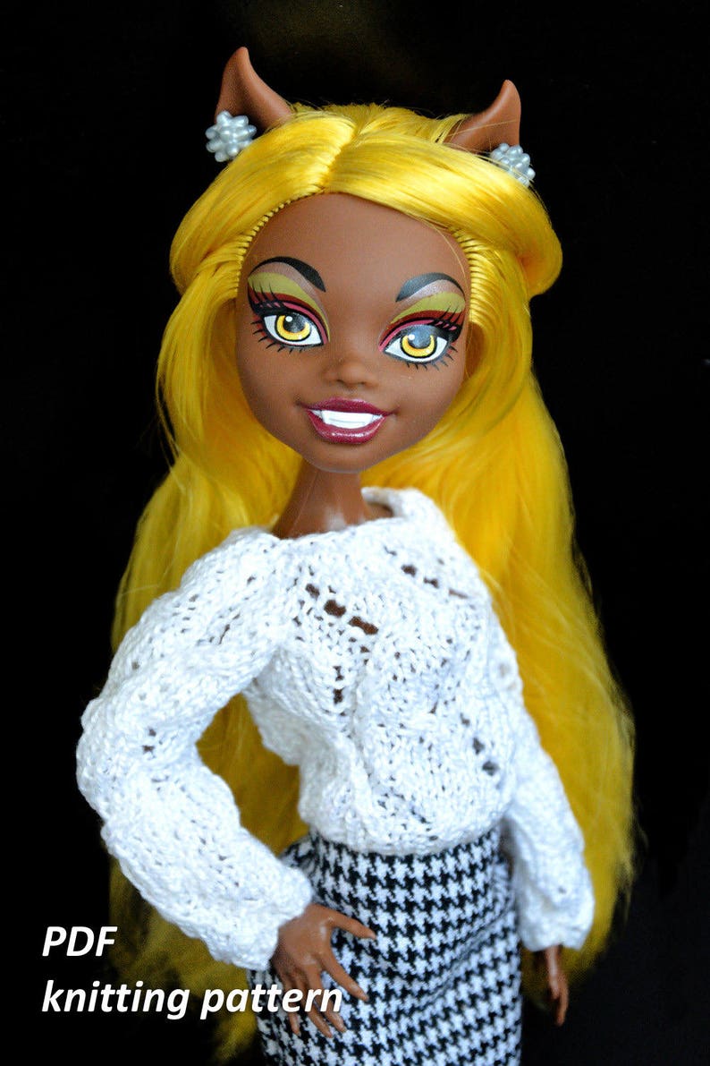 May include: A white knitted sweater with a delicate pattern, worn by a doll with yellow hair and brown skin. The doll is wearing a black and white houndstooth skirt. The image includes the text "PDF knitting pattern".