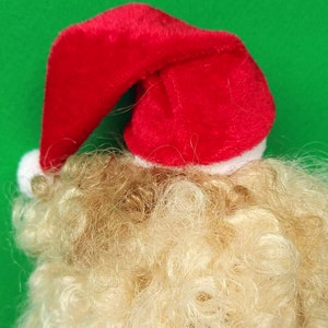 Puede incluir: Un gorro de Pap&aacute; Noel rojo con ribete blanco sobre una peluca rubia.