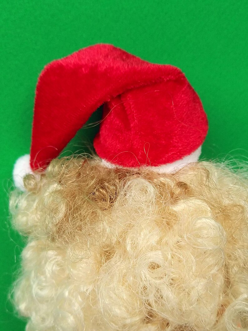Puede incluir: Un gorro de Pap&aacute; Noel rojo con ribete blanco sobre una peluca rubia.