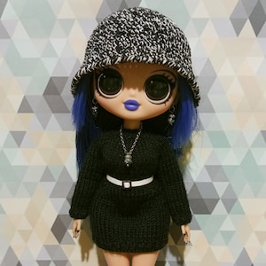 May include: A blue-haired doll wearing a black and white bucket hat, a black sweater dress with a white belt, and a silver necklace with a pendant. The doll has large blue eyes and blue lipstick.