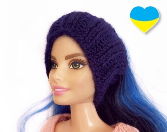 May include: A blue knitted headband with a braided pattern, worn by a doll with blue hair. The doll is looking to the right. A heart with the Ukrainian flag colors is in the background.