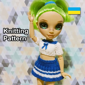 Puede incluir: Patrón de tejido para un atuendo de muñeca. El atuendo es un top de marinero blanco y azul y una falda azul con rayas blancas. La muñeca tiene el pelo verde y los ojos azules.